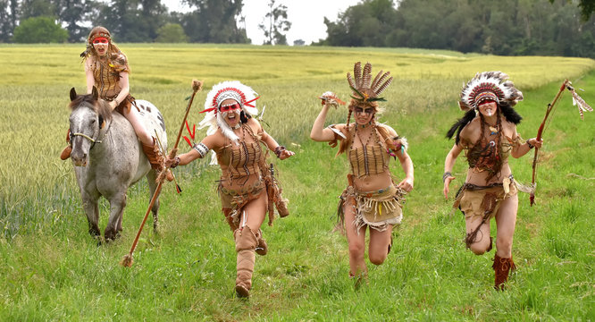 A group of four young Indian girls are on the attack. One  girl is on horseback while the other three are on foot.  They charge through a field running and screaming as  they attack.