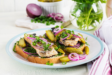 Traditional Dutch sandwich with herring and pickles cucumbers on white table. Smorrebrod.