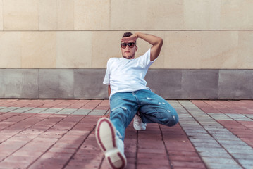 male athlete, sits down in distance, summer city, hip-hop style, break dancer. Free space...
