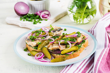 Traditional Dutch sandwich with herring and pickles cucumbers on white table. Smorrebrod.