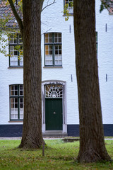 Edificio de piedra pintado de blanco con una puerta y ventanas verde 