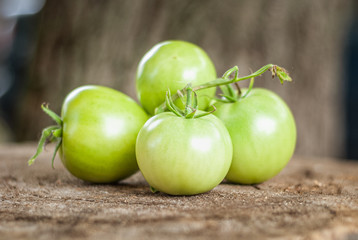 Green tomatoes on an old tree stump. Shallow depth of field.