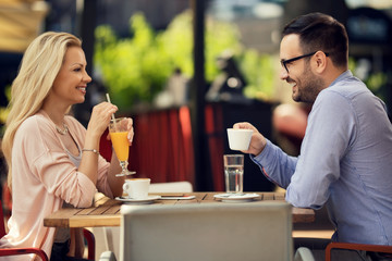 Happy couple communicating while relaxing in an outdoor cafe.
