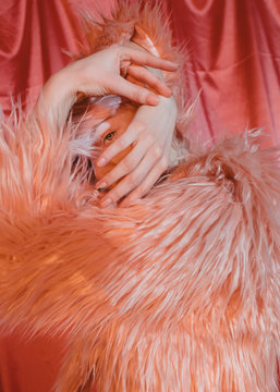 Model in fur jacket embracing face with hands