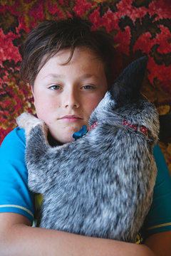 Adorable blue heeler puppy lying and cuddling with a young boy on red retro patterned carpet