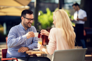 Happy man drinking coffee and talking to his girlfriend in a cafe.