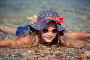 Portrait of cute cheerful, happy girl wearing hat and sunglasses, outdoor. Girl swimming in the sea