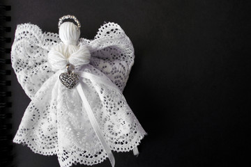 Christmas decoration. White angel on black background. Space for text or logos