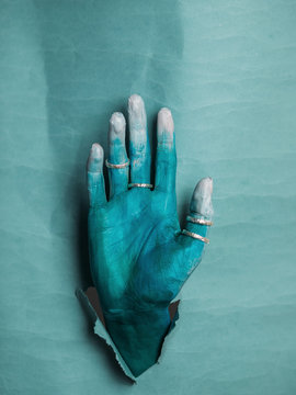 Crop female hand in blue paint and rings