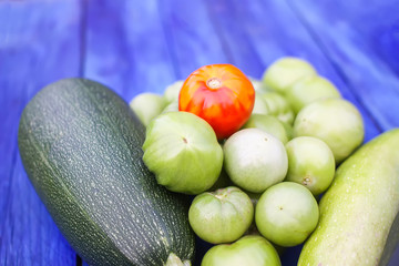 Zucchini and unripe tomatoes on wooden boards outdoors