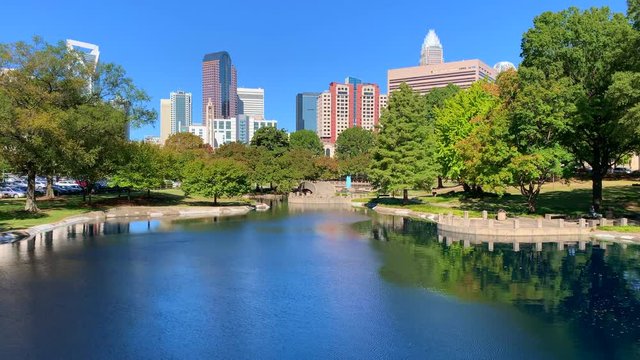 Charlotte, North Carolina city skyline in early autumn with blue skies and reflection in water