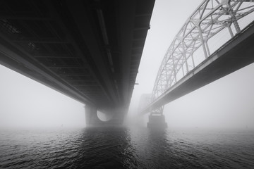 View under the big bridges across foggy Dnipro river in Kyiv. Ukraine.  Architecture in timeless black and white.