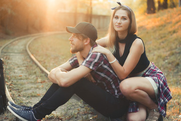 Young couple with suitcase late on train. Lovers are waiting for the train on rails. Desperate...