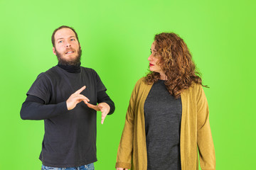 Young beautiful couple making funny gestures over green background. gracious and crazy expression