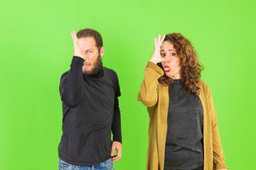 Young beautiful couple making funny gestures over green background. gracious and crazy expression