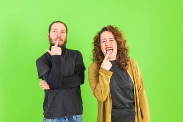 Young beautiful couple making funny gestures over green background. gracious and crazy expression