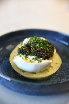 Close up of black caviar and egg on green tomato slice