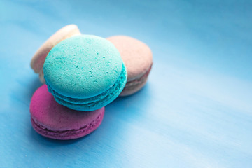 Sweet and bright colourful macarons on blue background. French dessert.