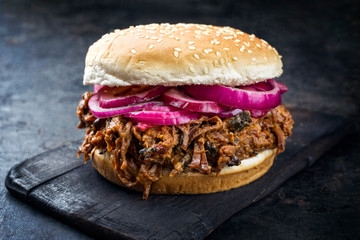 Traditional barbecue pulled beef burger offered with Carolina BBQ sauce, gherkin and onion rings as...