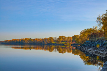 View looking down calm water at dawn with autumn trees and reflections nobody
