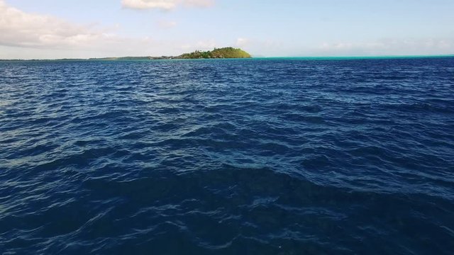 Tracking Shot of the Ocean and an Island Far Ahead Under Blue Sky and Clouds