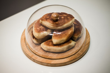 Pies on a wooden board under a glass lid