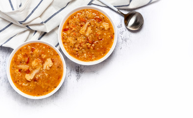Dal - Traditional spicy Indian soup of red lentils and vegetables in a white bowl on a grey background, top view, copy space. Indian and vegetarian food.