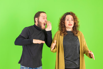 Young beautiful couple over green background, mad, shouting and yelling with aggressive expression.Frustration and crazy concept.