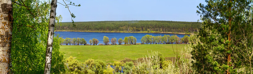 Springtime landscape, banner, panorama - view through the pines and birch on Desna river with flooded meadows and forests in the north of Ukraine