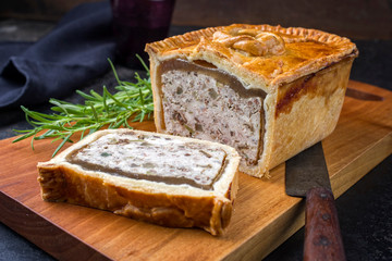 Traditional French Pate en croute with chicken offered as closeup on a modern design cutting board