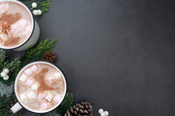 Hot chocolate mugs with marshmallows. Flat lay with fir branches. Gray background. Warm winter...