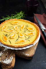 Traditional French Autumn pumpkin tarte offered as closeup in a backing form on an old wooden cutting board