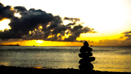 Fototapeta stos kamieni  na plaży o wschodzie słońca obraz
