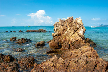 Beautiful cliff in the azure sea with clear water and boats on the horizon. Cumulus clouds in the...