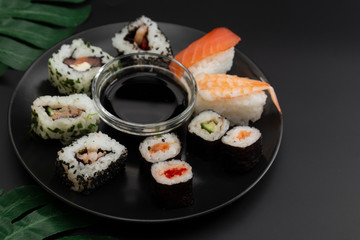 Sushi on black dish isolated on black background with copy space. Top view.
