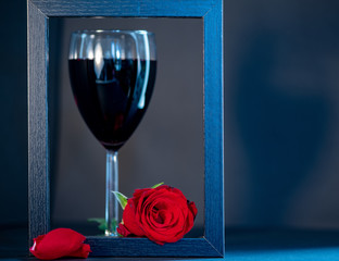 glass of red wine and rose on black background