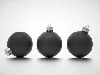 Three matte black Christmas ball decorations on grey studio