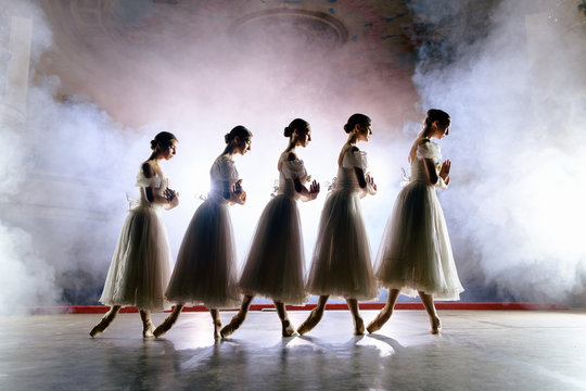 Row of ballerinas in dresses posing on scene