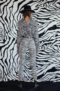 Anonymous model in striped outfit near zebra wall