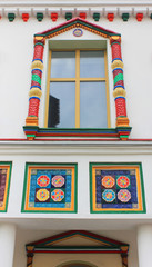 Fototapeta na wymiar Ornamental house facade design. White stone with window frame and decorative tiles, vertical view 