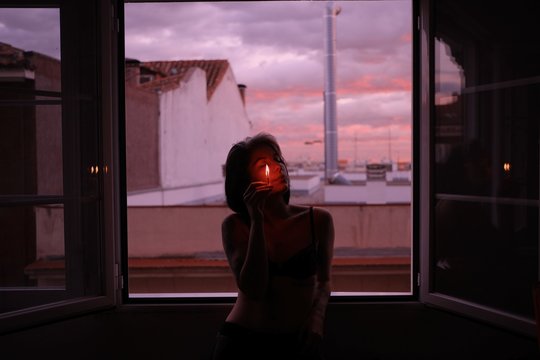 Woman holding burning match during sunset