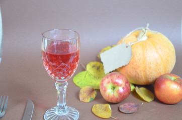 Thanksgiving Day. Pumpkin, pumpkin with autumn leaves and apples. Autumn harvest on a brown background.   set table for celebration. fork and knife still life with bottle glass of red wine