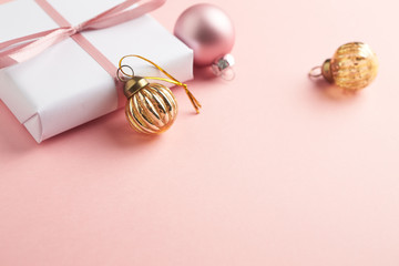 Christmas baubles and Christmas present. Bright paper background. Close up. Copy space. 