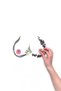 Women's bare breasts made out of flowers on an off-white background.