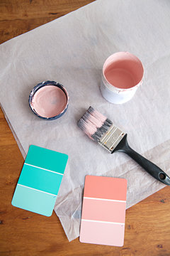 Pink and green color swatches for paint on table top with paint brush and paint