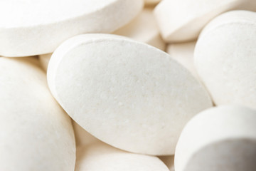 Fototapeta na wymiar Group of white medical supplement pills, macro image