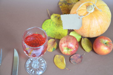 Obraz na płótnie Canvas Thanksgiving Day. Pumpkin, pumpkin with autumn leaves and apples. Autumn harvest on a brown background. set table for celebration. fork and knife still life with bottle glass of red wine