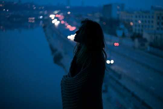 portrait girl silhouette on the background of the city and river in the evening