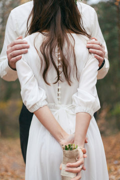 hands of the bridegroom on the shoulders of the bride
