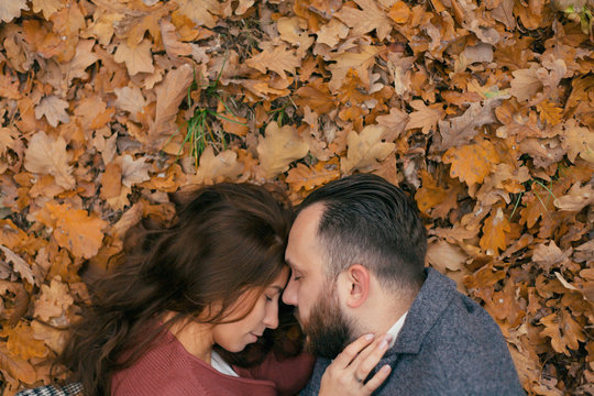 portrait of a guy and a girl hugging in the leaves from above angle